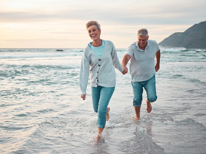 A retired couple walking down a beautiful beach